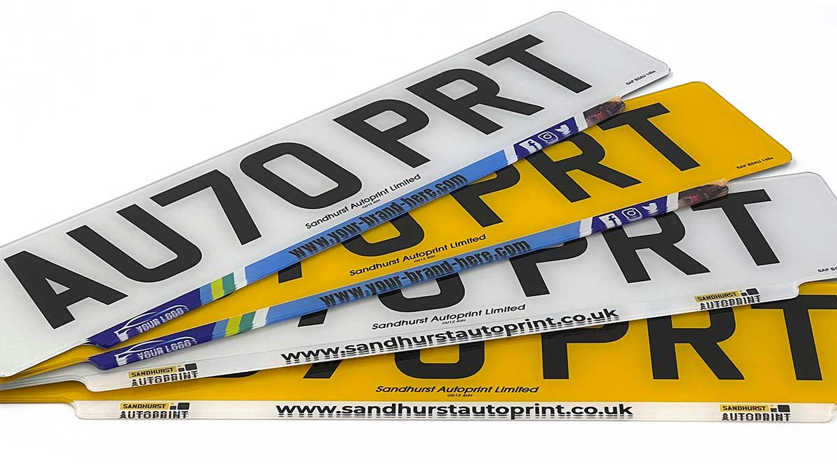 A fan of white and yellow number plates with dealer branding strips