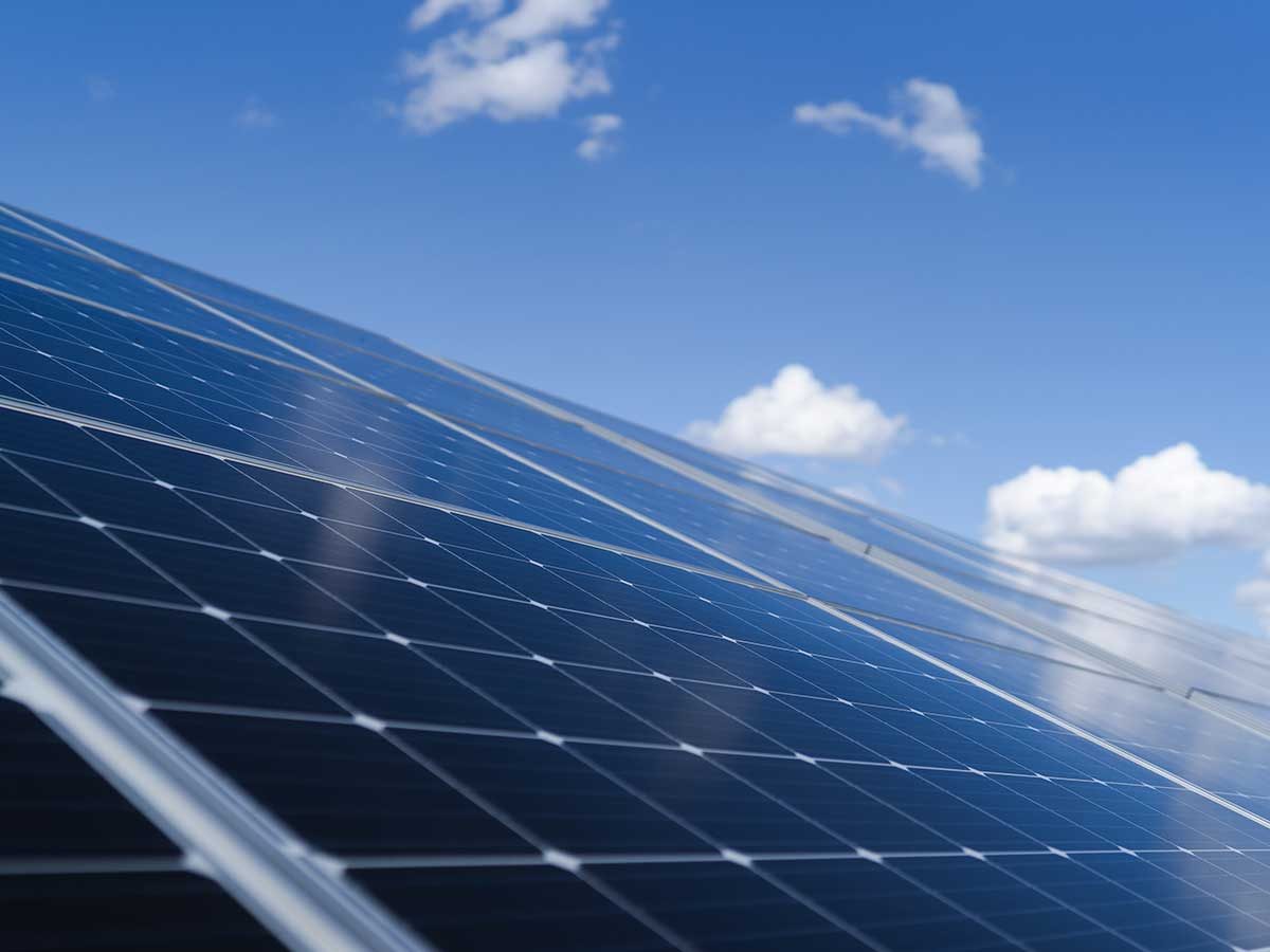 Rows of solar panels under a blue sky with light cloud